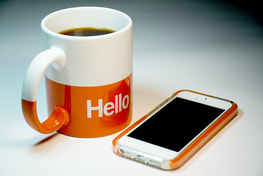 Orange and white mug next to a cellphone